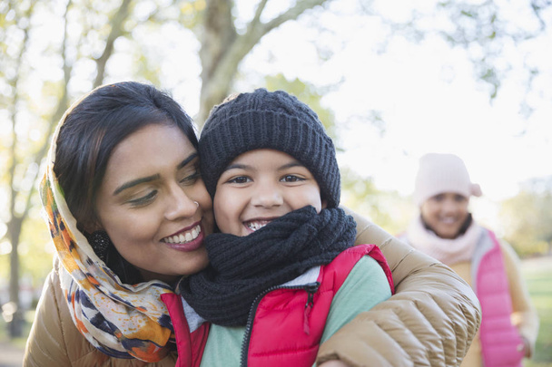 Retrato mãe muçulmana feliz no hijab abraçando filho no parque de outono
 - Foto, Imagem