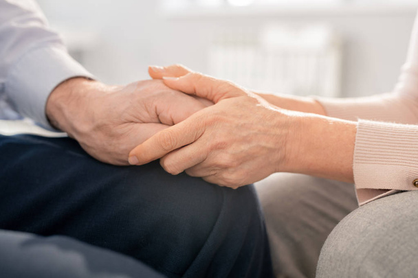unterstützende reife Frau hält die Hand eines älteren Mannes, während sie sich um ihn kümmert und Mitgefühl ausdrückt - Foto, Bild