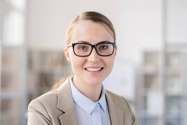 Retrato de satisfeito confiante jovem especialista em negócios do sexo feminino em óculos trabalhando em escritório moderno
 - Foto, Imagem