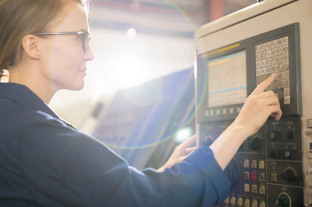 Ingénieur technique contemporain appuyant sur l'un des boutons du panneau de commande de la machine industrielle pendant le travail
 - Photo, image