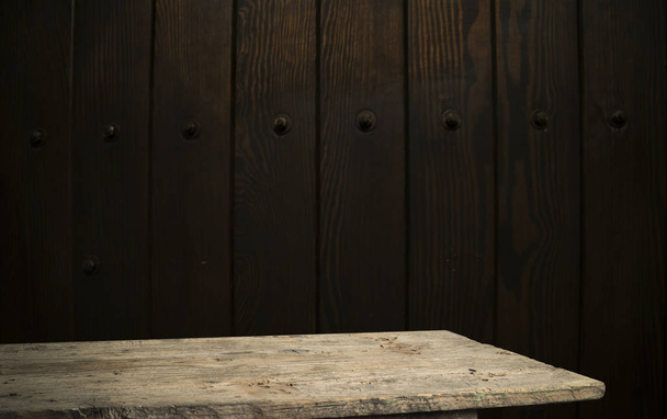 Vybrané zaměření prázdný hnědý dřevěný stůl a textura stěny nebo staré černé cihly stěna rozmazat obrázek na pozadí. pro fotomontáž nebo zobrazení výrobku - Fotografie, Obrázek