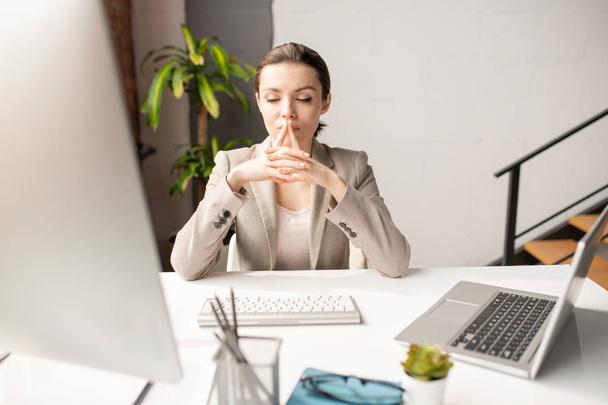 junge nachdenkliche Geschäftsfrau konzentriert sich auf Computerarbeit, während sie im Büro vor dem Monitor sitzt - Foto, Bild