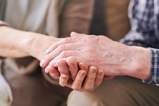 Рука старшего пенсионера сверх руки жены, когда они сидели рядом друг с другом.
 - Фото, изображение
