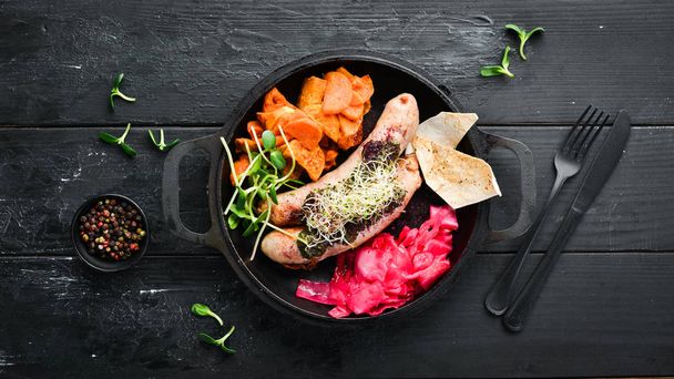 Baked sausages, sweet potatoes and cabbage. In the plate. Top view. Free space for your text. Rustic style. - 写真・画像