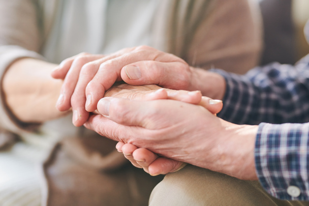 Старший мужчина и женщина держатся за руки друг друга как символ единства, поддержки и заботы
 - Фото, изображение