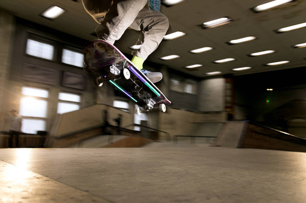 Action shot of unrecognizable young man doing skating stunt at skateboard park, shot with flash - Photo, Image