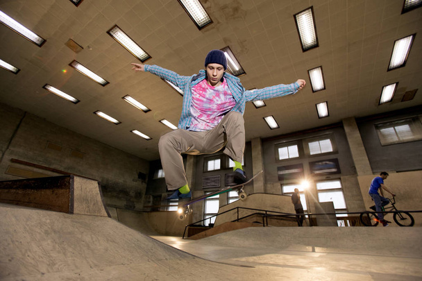 Actie shot van jonge man doen schaatsen stunt op skateboard park, geschoten met Flash - Foto, afbeelding
