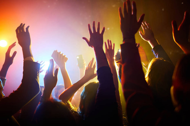 Posluchači užívající představení: dav neidentifikovatelných lidí, kteří mávají rukama ve vzduchu a podporují oblíbenou zpěvačku na koncertě - Fotografie, Obrázek