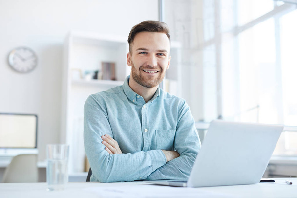 Portrait d'un bel entrepreneur souriant joyeusement à la caméra tout en posant sur le lieu de travail dans le bureau, espace de copie
 - Photo, image