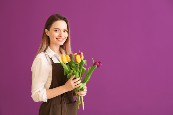 Jonge vrouwelijke bloemist met boeket op kleur achtergrond - Foto, afbeelding