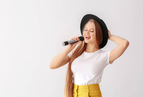 schöne Sängerin mit Mikrofon auf hellem Hintergrund - Foto, Bild