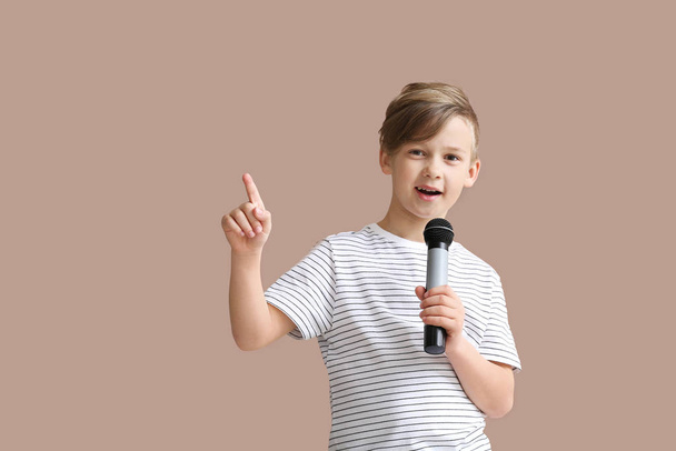 Симпатичный маленький мальчик с микрофоном поет на фоне цвета
 - Фото, изображение