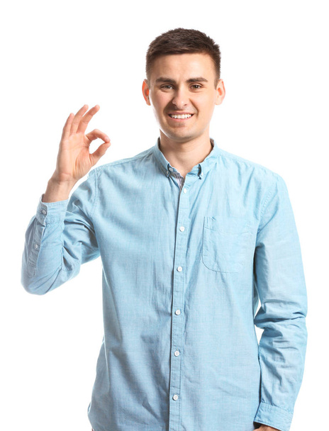 Young deaf mute man using sign language on white background - Foto, Imagem