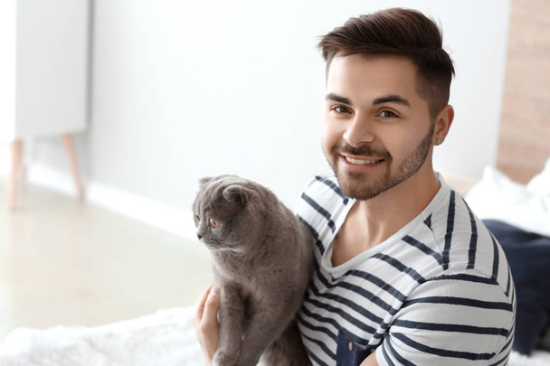 Joven hombre con lindo divertido gato en casa
 - Foto, imagen