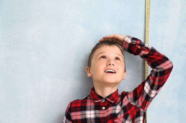 Cute little boy measuring height near color wall - Foto, immagini