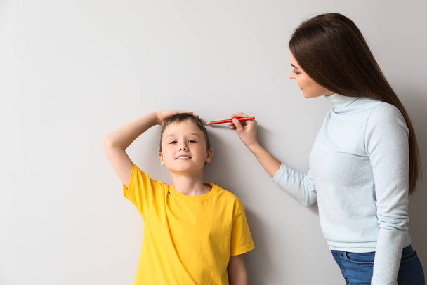 Mother measuring height of her son near wall - Photo, Image