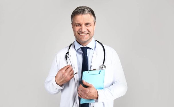 Handsome mature doctor on grey background - Photo, Image