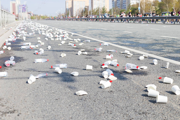 Un montón de vasos de plástico y botellas vacías en las calles mientras una maratón corre
 - Foto, Imagen
