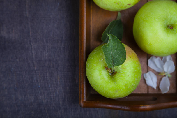 Green apples on a wooden tray. - 写真・画像