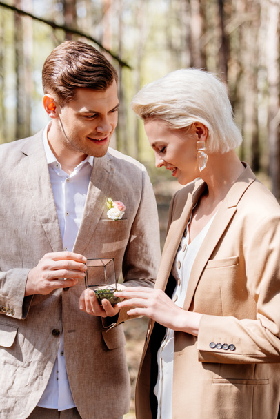 Homme souriant et heureux faisant une demande en mariage à une belle femme dans la forêt
 - Photo, image