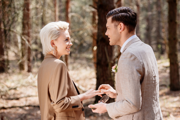 Side view of smiling man proposing to woman in forest - Foto, Imagem