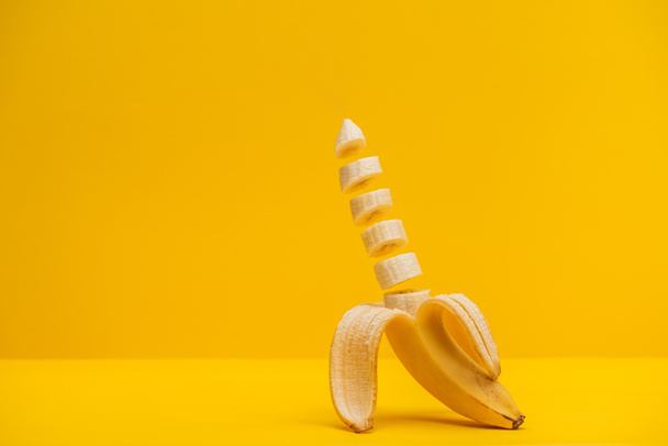 Half sliced fresh sweet tasty banana isolated on yellow - Fotografie, Obrázek