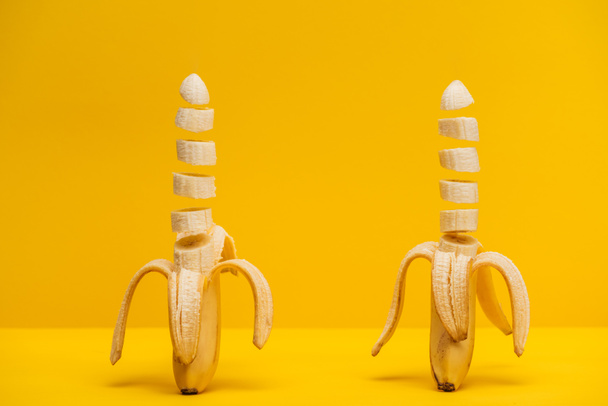 Two freshly sliced delicious bananas isolated on yellow - Фото, изображение