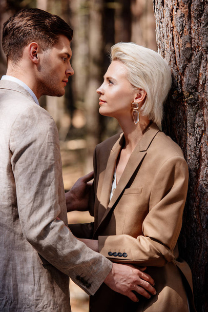 casal elegante em desgaste formal olhando uns para os outros na floresta
 - Foto, Imagem