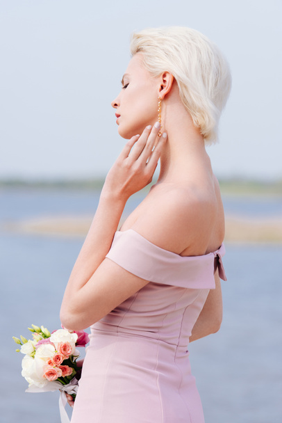 pensive blonde girl in pink dress holding bouquet - Fotoğraf, Görsel