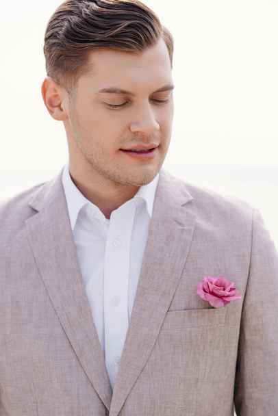 pensive bridegroom in formal wear with boutonniere with closed eyes - Fotó, kép
