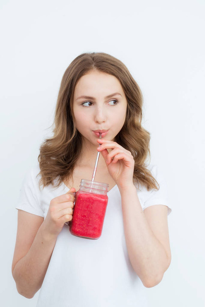 Beautiful happy young girl drinks organic berry, fruit smoothie on a white background. - Foto, Imagem