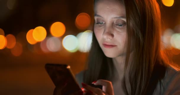 Giovane ragazza nella città di notte scrive messaggi di testo in uno smartphone
 - Filmati, video
