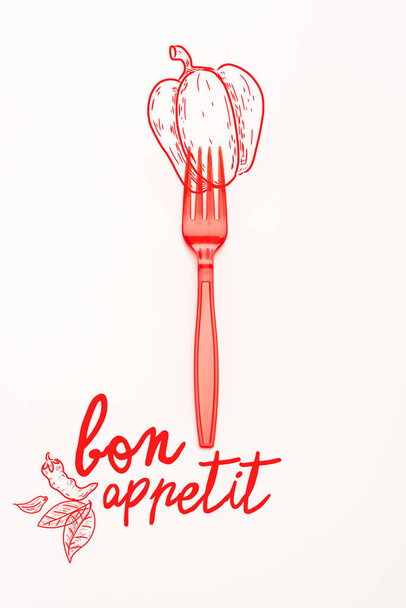 red plastic bright fork with bell pepper illustration and bon appetit lettering isolated on white  - Photo, Image
