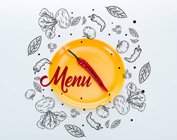 top view of red chili pepper on bright yellow plate with menu lettering on white background - Zdjęcie, obraz