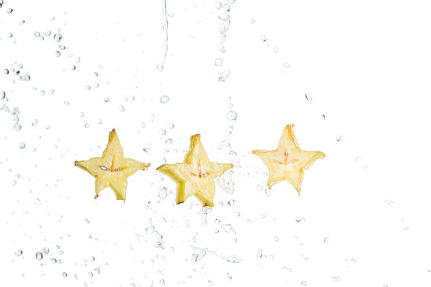 Свежие экзотические куски фруктов звезды и капли воды изолированы на белом
 - Фото, изображение