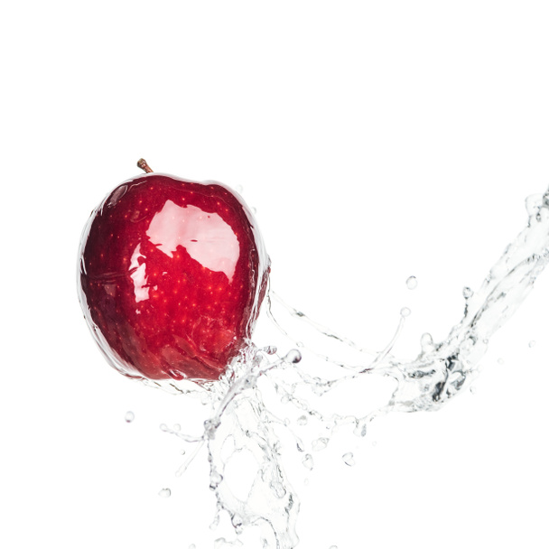 hele natte rijpe rode appel en helder water plons geïsoleerd op wit - Foto, afbeelding