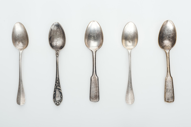 top view of shiny aged silver empty spoons in row on white background - Photo, Image