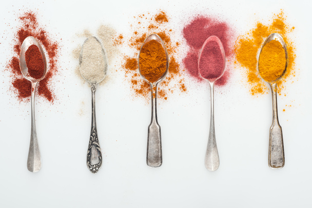 top view of various colorful spices in silver spoons on white background - Photo, Image