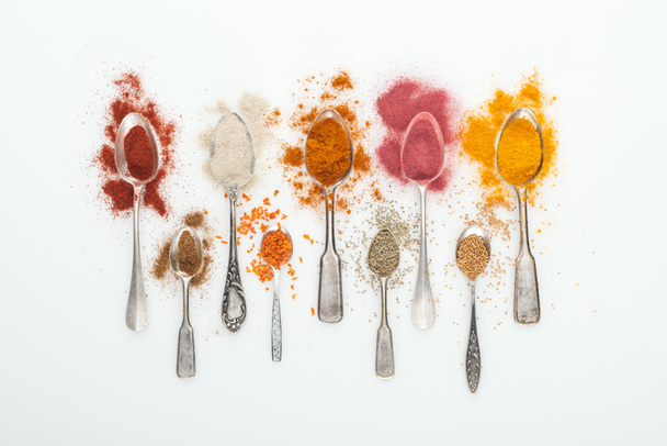 top view of colorful spices in silver spoons on white background - Photo, Image