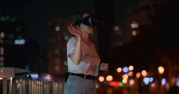 Fiatal nő virtuális valóság szemüveg az éjszakában város mozog a kezét - Felvétel, videó