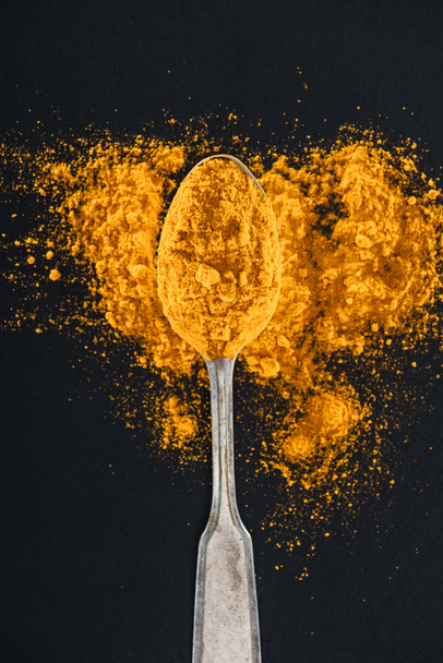 top view of curry powder in silver spoon on black background - Photo, Image