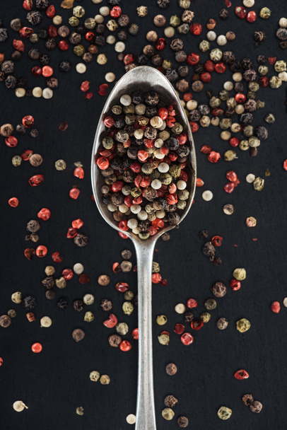 top view of mix pepper spice in silver spoon on black background - Foto, afbeelding