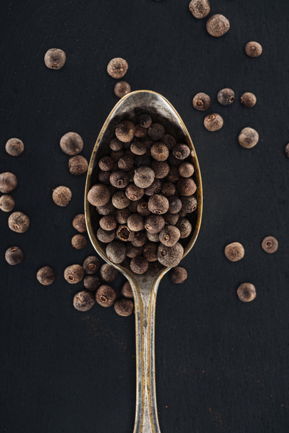 top view of black pepper in silver spoon on black background - Photo, Image