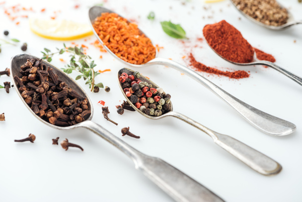 close up view of colorful indian spices in silver spoons on white background - Photo, Image