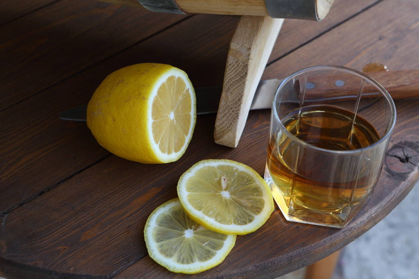 Brandy with lemon. A glass of brandy around an oak barrel - Фото, изображение