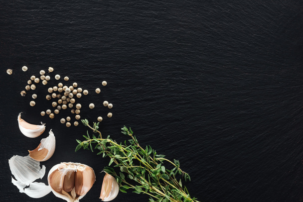 vista dall'alto del pepe bianco su sfondo nero vicino agli spicchi d'aglio e al timo
 - Foto, immagini
