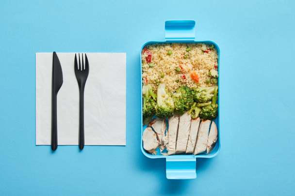 Top view of lunch box with risotto, broccoli and chicken on blue background - Photo, Image