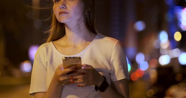 Mladá žena v noci ve městě volá taxi přes smartphone - Záběry, video
