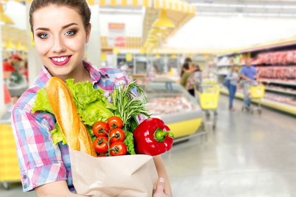 Sorrindo mulher feliz gostando de fazer compras no supermercado, segurando legumes em saco ecológico
 - Foto, Imagem