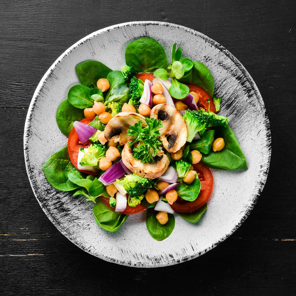 Salad with mushrooms, spinach, Turkish peas and onion in a plate on a wooden background Top view. Free space for your text. Flat lay - 写真・画像